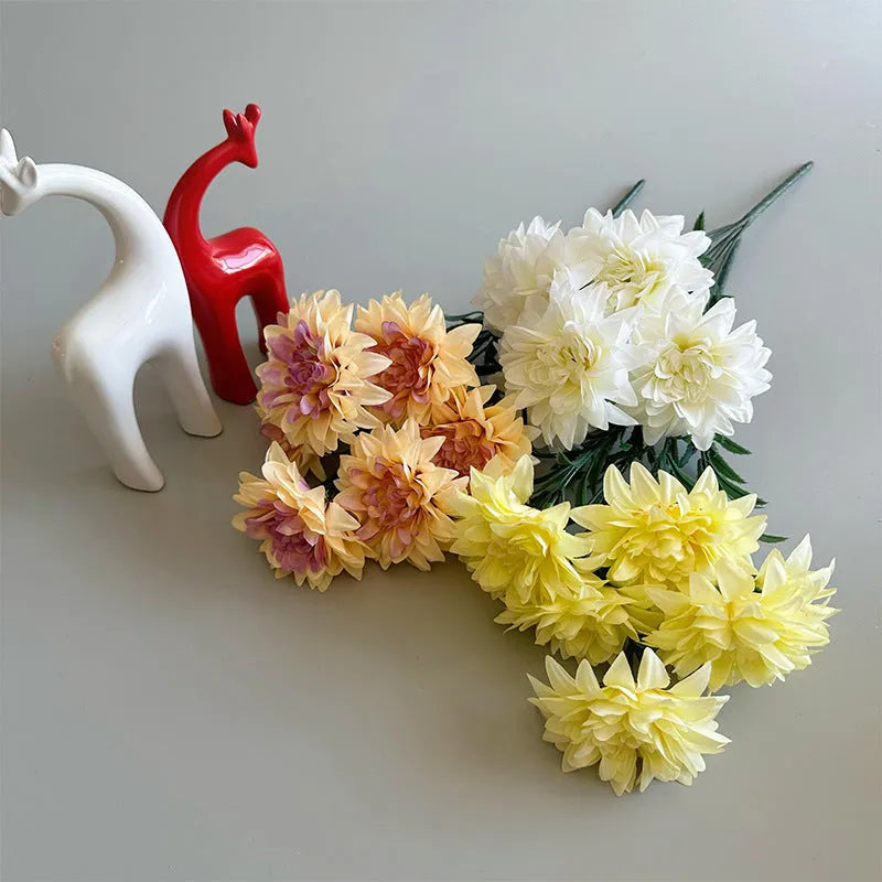 A fan-shaped display of silk dahlia, peony and rose flowers in a yellow colour on a wooden desktop.