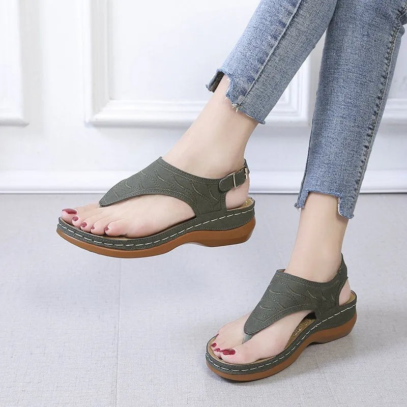 Women's casual wedge heel flip flop sandals with an adjustable buckle strap on the back, shown in a solid colour.
