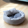 Grey round pet bed for small dogs and cats with raised edges and removable pillow on non-slip base