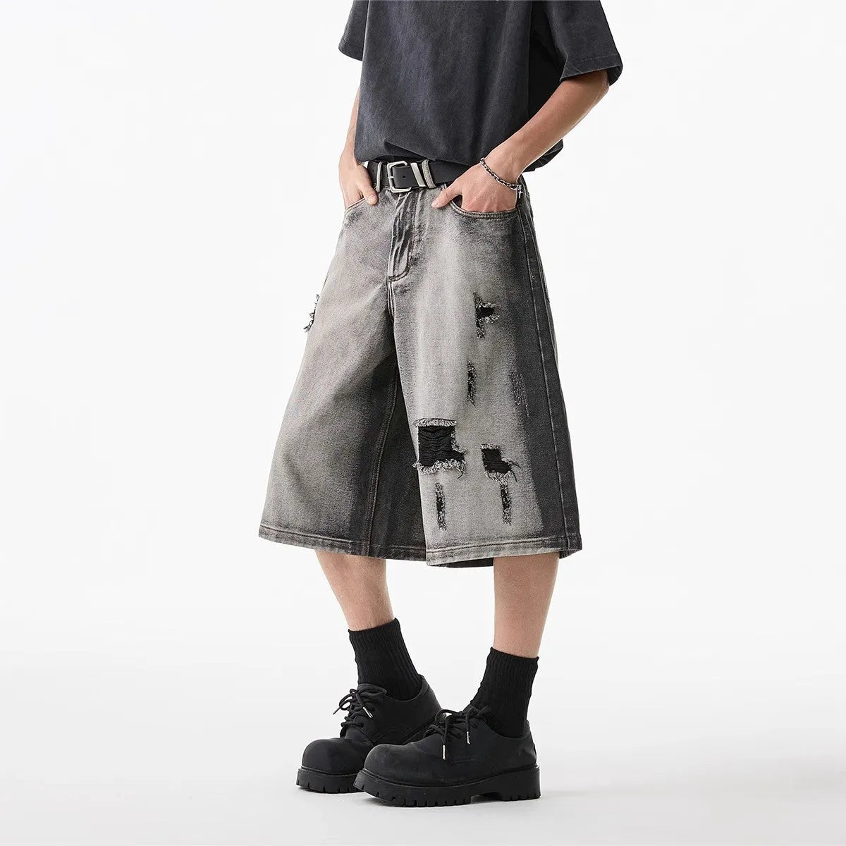 Grey denim shorts with washed finish and hole details, loose fit cropped length
