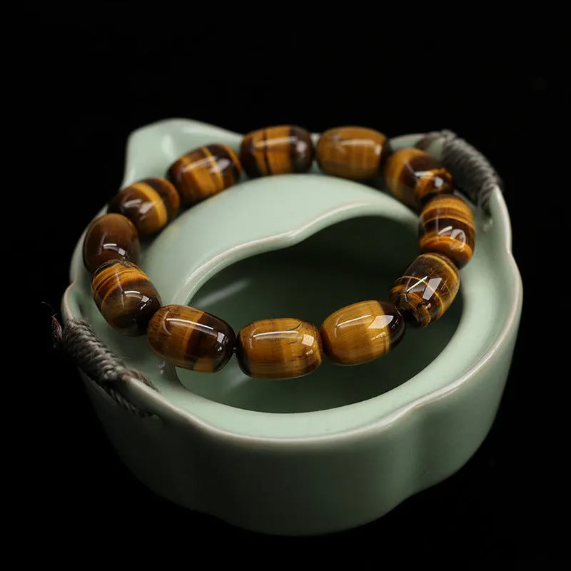 Close-up of a natural yellow Tiger Eye gemstone beaded bracelet with cat's eye effect on a wrist.