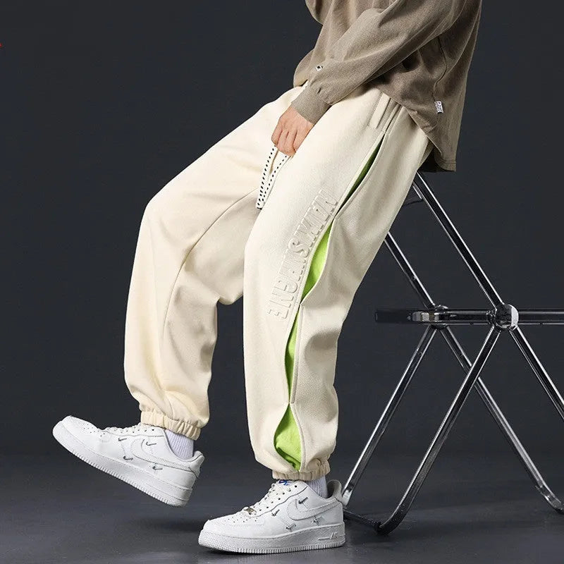 Men's ankle banded trousers in micro-elastic cotton with collage stitching, showing skinny leg and mid-waist fit.