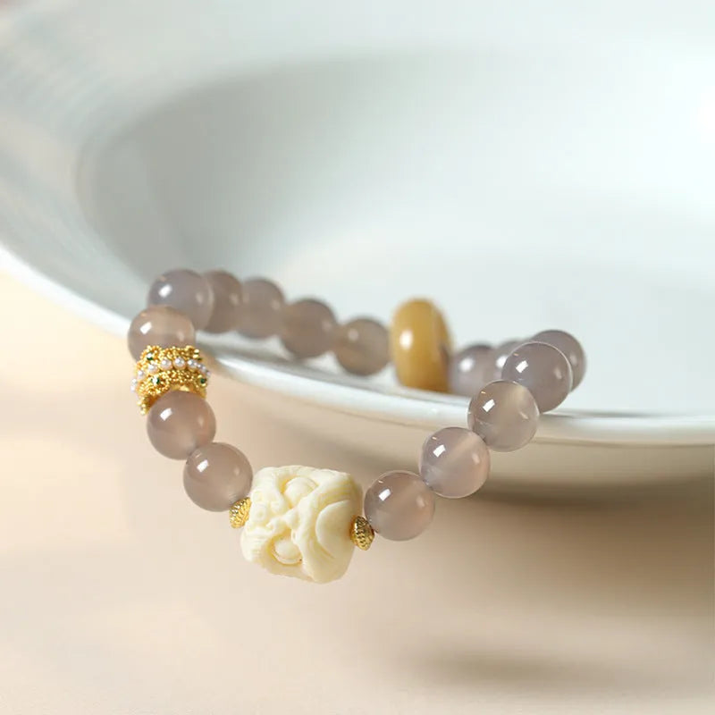 Hand-woven bracelet with round grey agate and mellite beads on a white background.
