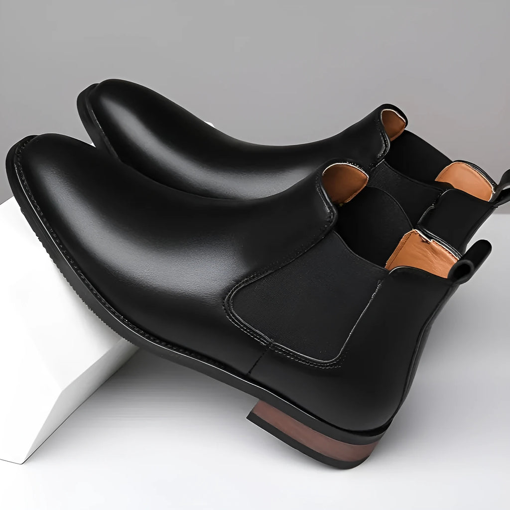 Men's black pointed toe Chelsea boots with a high-top design and decorative stitching on a rubber sole.