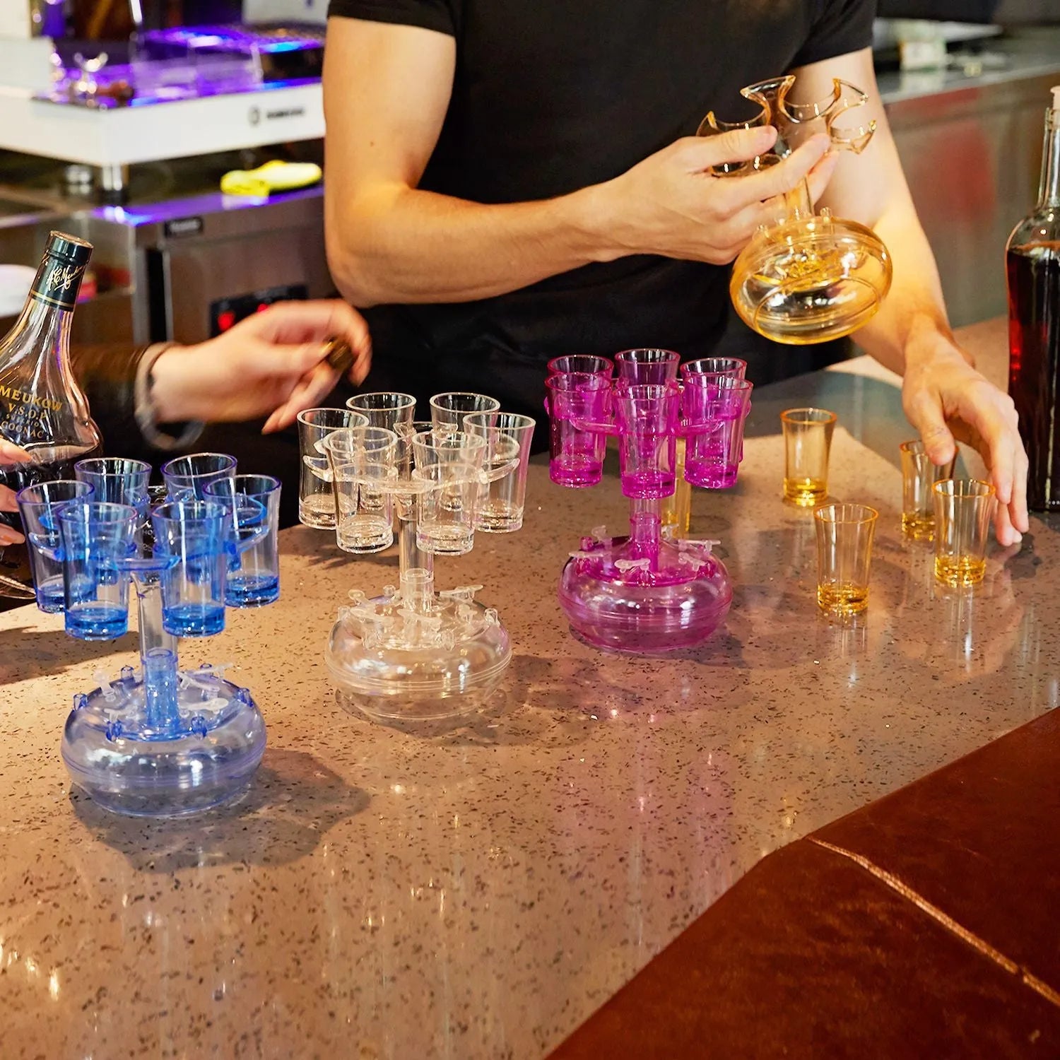 Transparent 6-shot glass dispenser rack with six shot glasses on a bar table.
