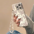 Transparent three-in-one mirror phone case for iPhone with detachable bracelet, showing bow decoration.
