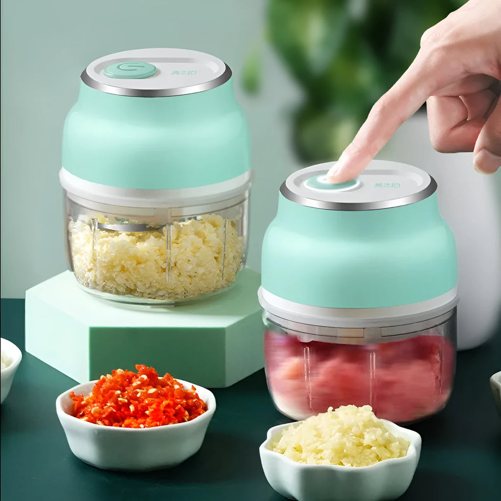 Portable electric mini food chopper with transparent cup and stainless steel blade on a kitchen counter