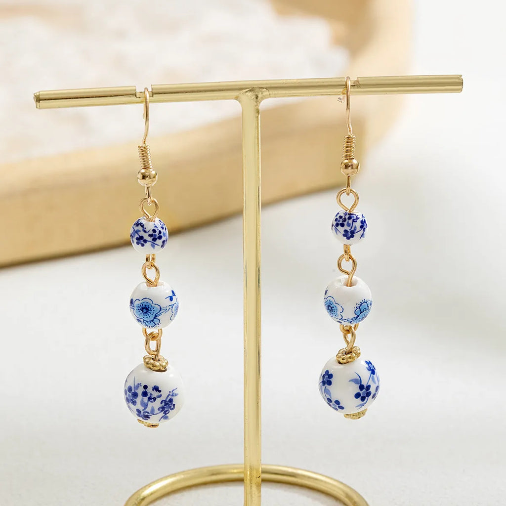 Long blue and white porcelain ceramic bead retro geometric earrings with alloy electroplated frame.